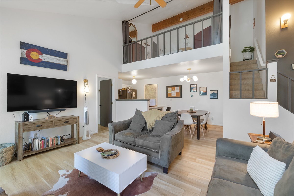 Living room with kitchen, dining area and loft in background
