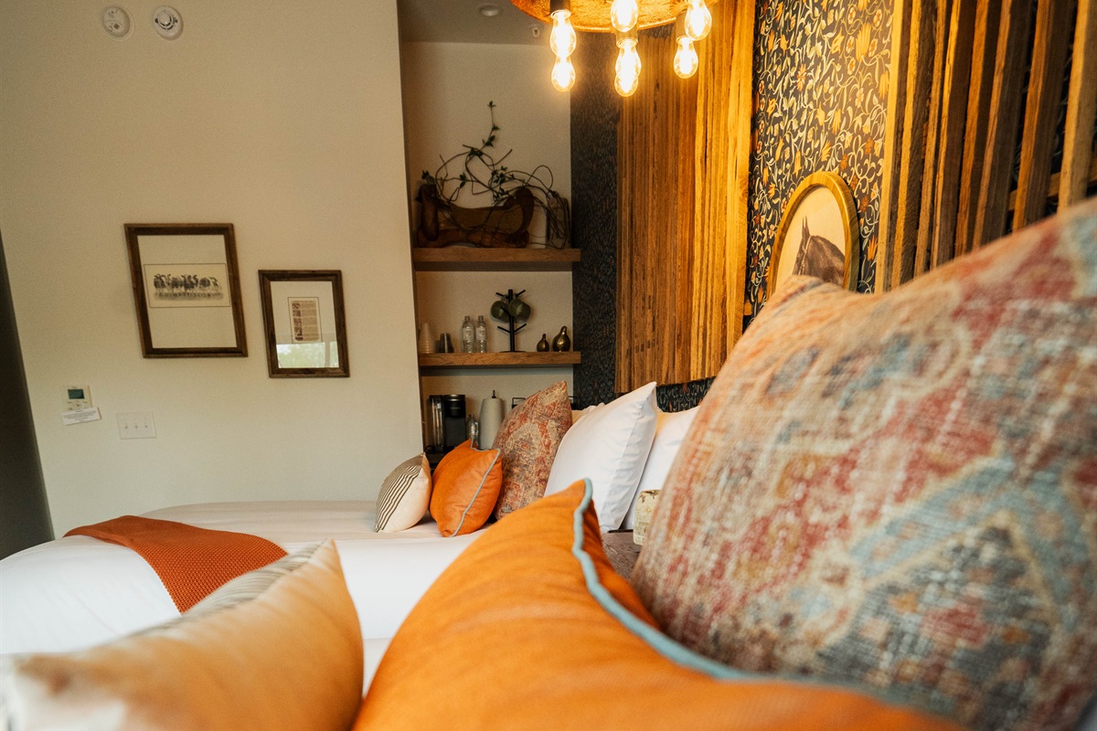 The Corral Suite from a fresh angle — two queen beds, designer pendant lighting, and the property's signature feature wall.