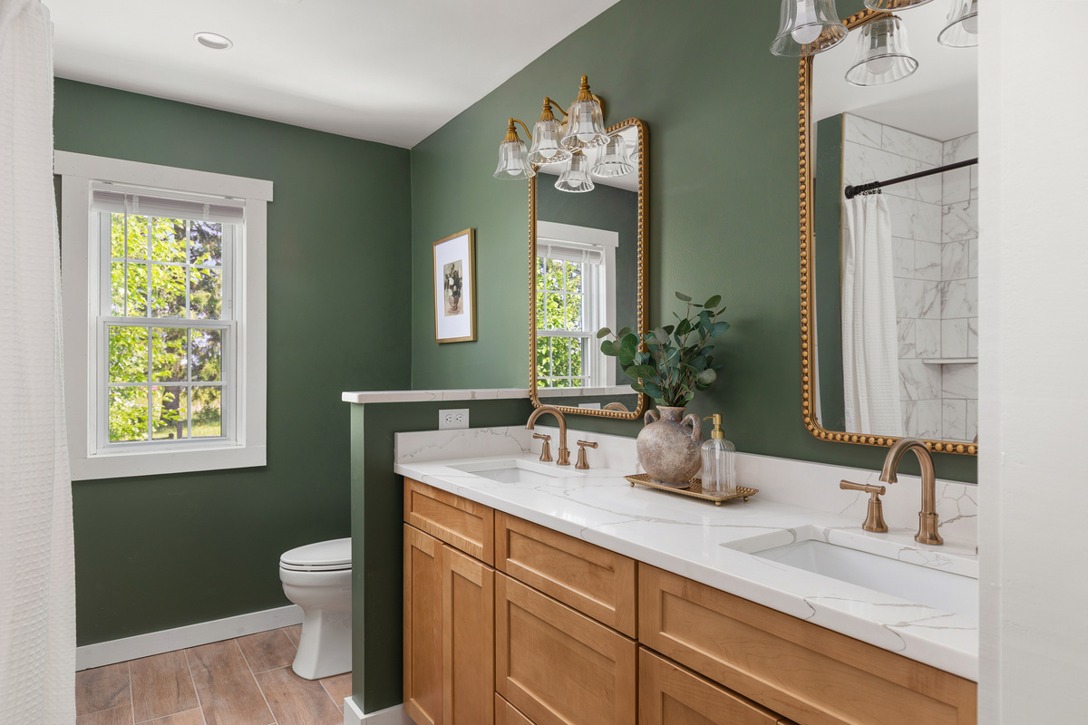 Spa inspired downstairs bath featuring a double vanity, custom tile shower, warm brass finishes, and rich green walls. Thoughtfully designed with both style and function in mind for families and groups. 
