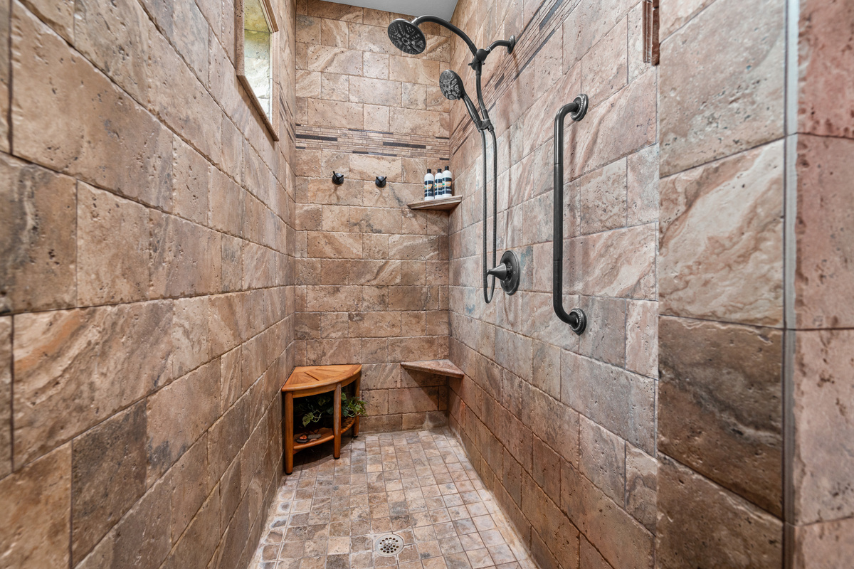 Spa-inspired walk-in shower with beautiful stone tile finishes and dual shower heads for a luxurious retreat experience.