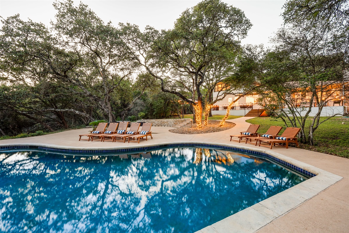 A peaceful poolside setting surrounded by nature — perfect for lounging under the trees and soaking in a quiet retreat.