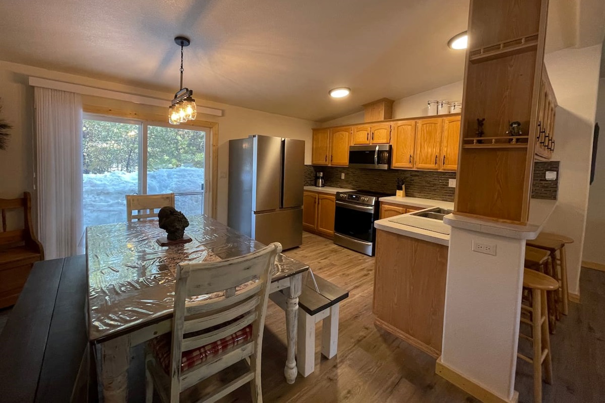 Kitchen with Updated Appliances, Backsplash, Faucet, Cupboard Door Handles, Light, Table, and Flooring