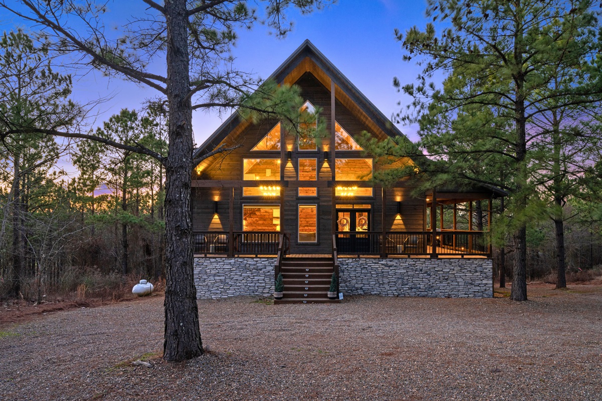 The cabin looks absolutely stunning from this view, with tall windows and that classic A-frame style that fits perfectly in the woods.