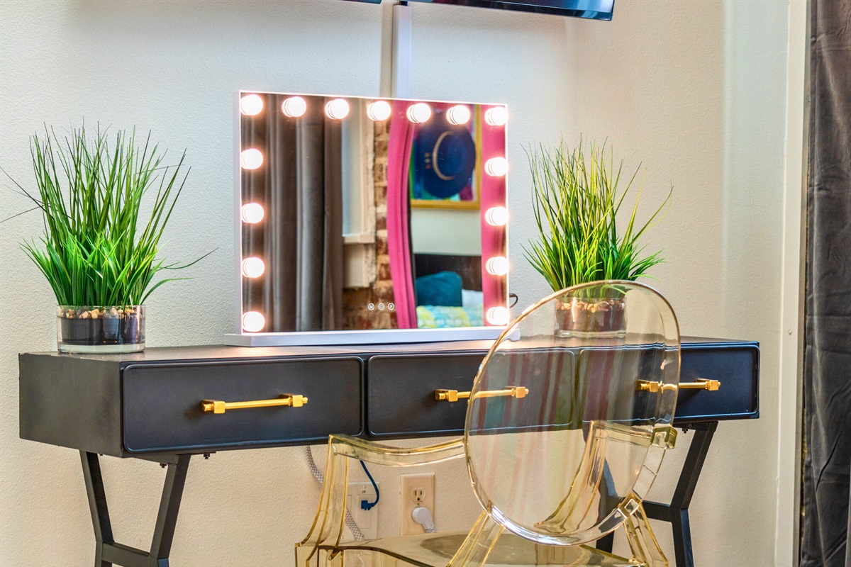 A chic vanity area, complete with a large mirror and bright lighting, offers the perfect spot to get ready in the morning or unwind at night.