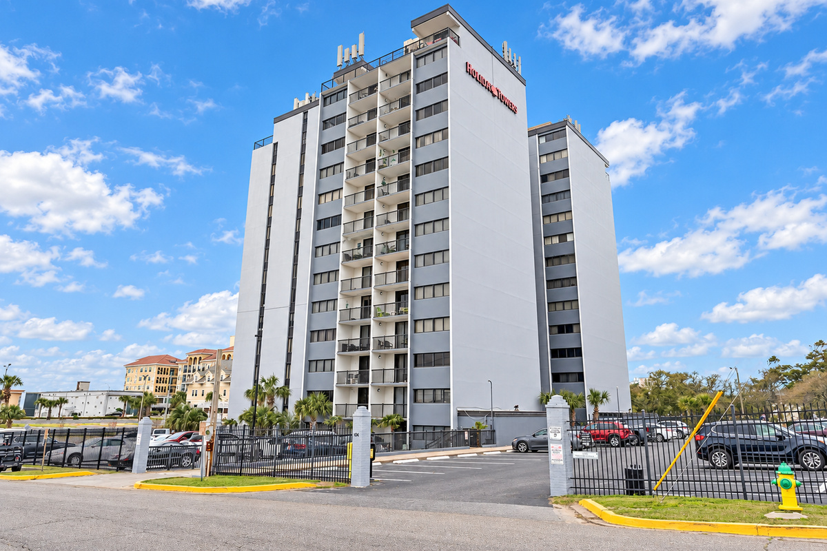 Aerial view of Holiday Towers with shared pool, hot tub, sports court, parking, and Myrtle Beach attractions nearby.