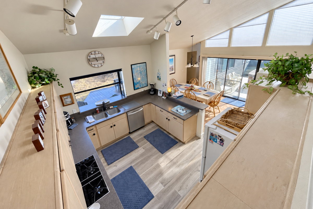 Open Floor plan from Living Room upstairs. Looking down on kitchen and dining area. Natural lighting from vaulted ceilings and skylight windows.