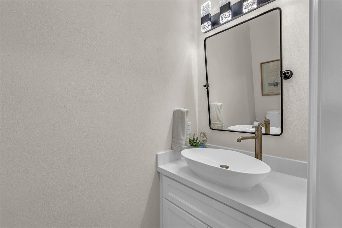 Costa Cristal Half Bath: Stylish powder room with a modern vanity and mirror, offering comfort and convenience for guests.