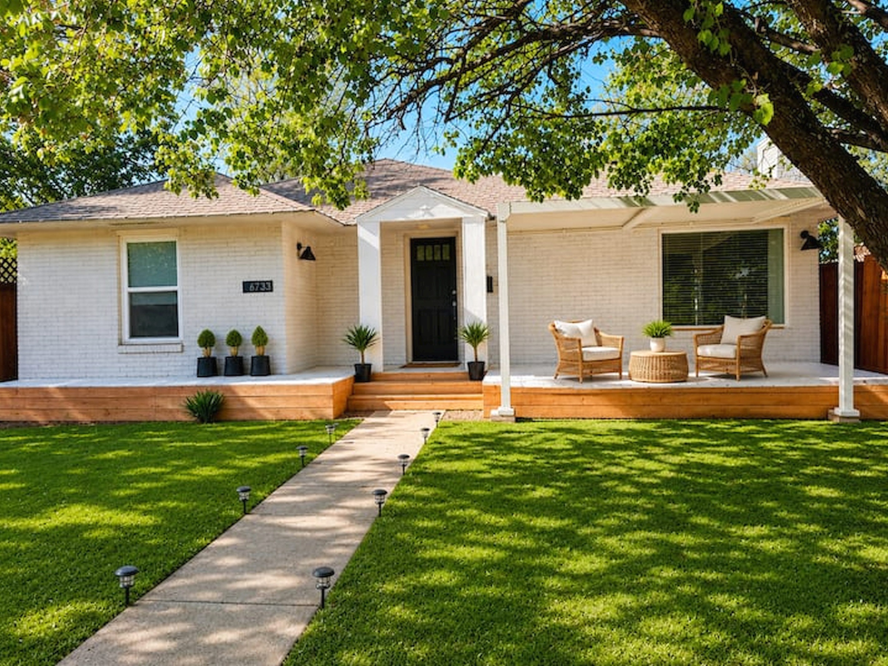 Charming modern home with inviting front porch seating, fresh landscaping, and a warm boutique-style welcome