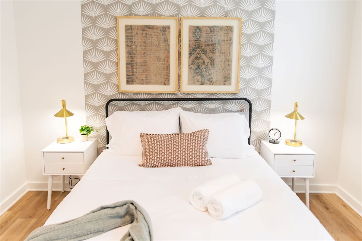 Elegant bedroom with a white interior, featuring two bedside lamps on either side of a table, creating a soft, ambient glow for a cozy and restful atmosphere.