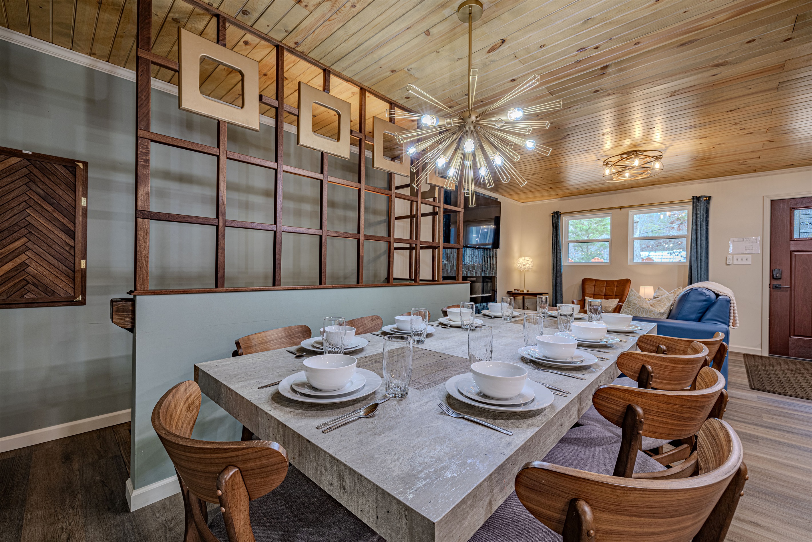 Gather for a feast at the large dining table featuring iconic mid-century seating and a stunning starburst chandelier.
