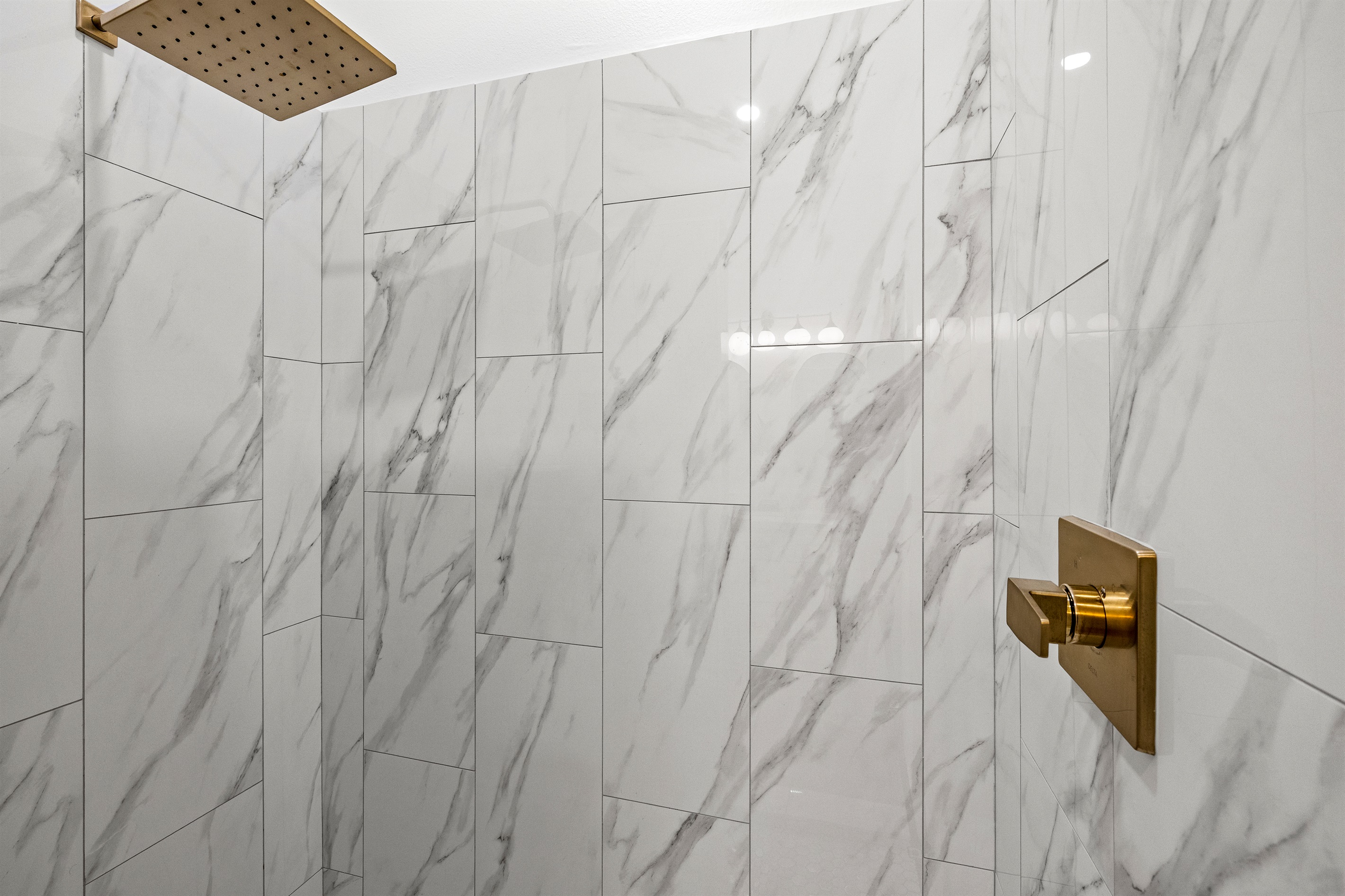 Spacious shower with rainfall shower head.