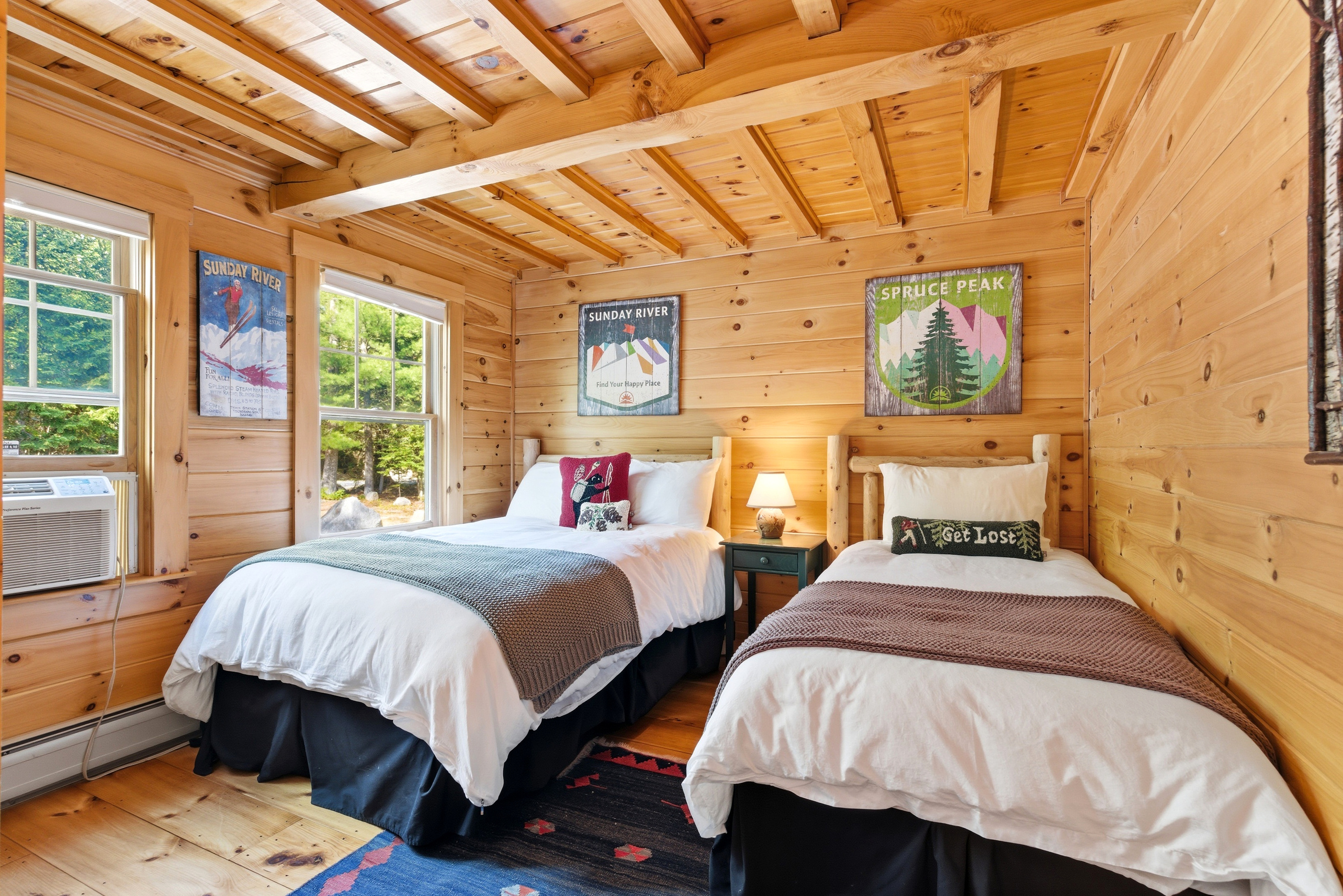 Perfect for families or friends, this inviting bedroom offers two comfortable beds in a warm cabin setting.