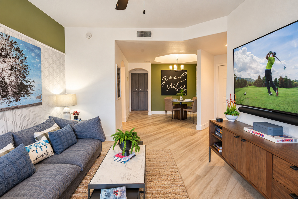 - Lounge in a stylish living room blending comfort and modern design   - Natural light and green accent walls bring warmth to the open layout   - Perfect for unwinding after pool days or nearby golf adventures