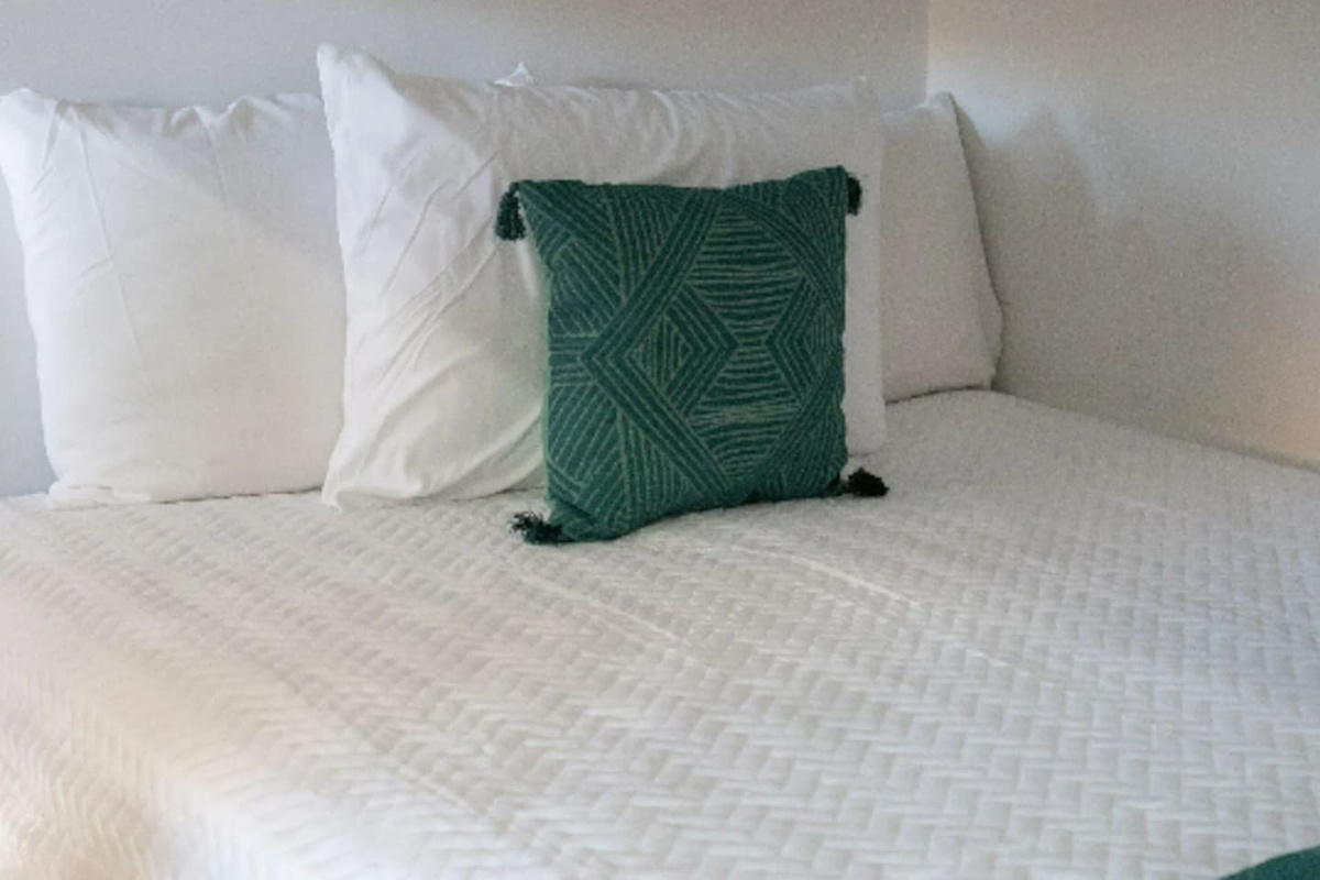 Crisp white linens get a pop of personality from a hand-woven, tasseled accent pillow, keeping the space playful without losing that put-together feel.