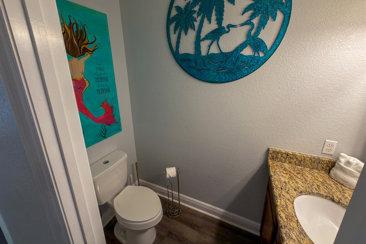 Bright beach-inspired décor and playful coastal touches bring personality and charm to the hallway half bath.