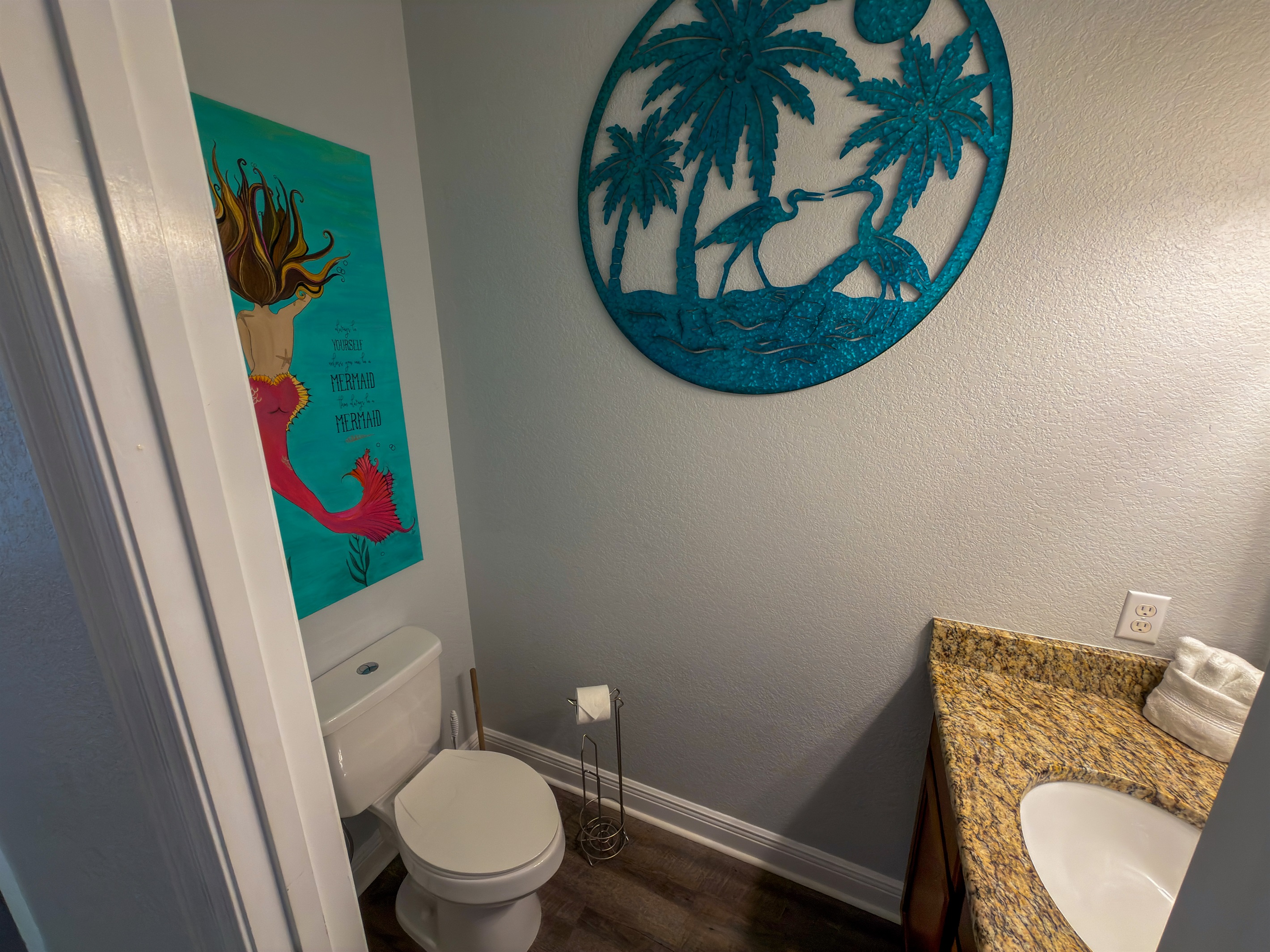 Bright beach-inspired décor and playful coastal touches bring personality and charm to the hallway half bath.