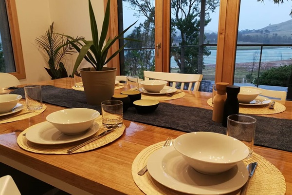 Dining table in front of bifolds that open towards verandah