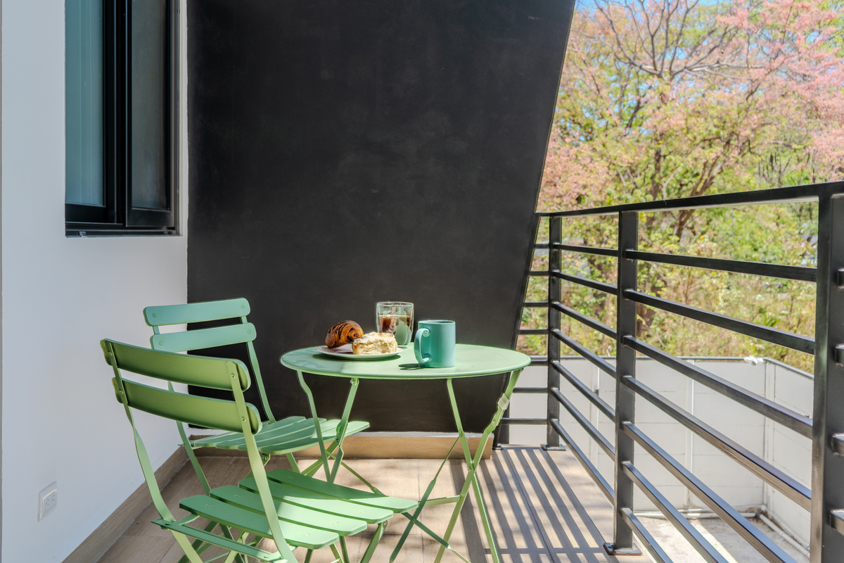 Morning on the balcony. Treetop views, bistro table, slow start.