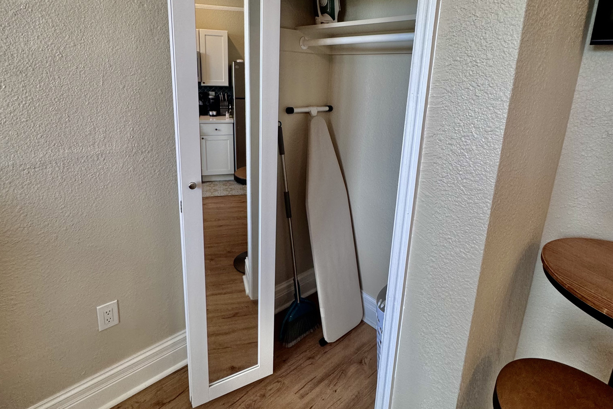 Full closet with felt hangers, iron and ironing board.