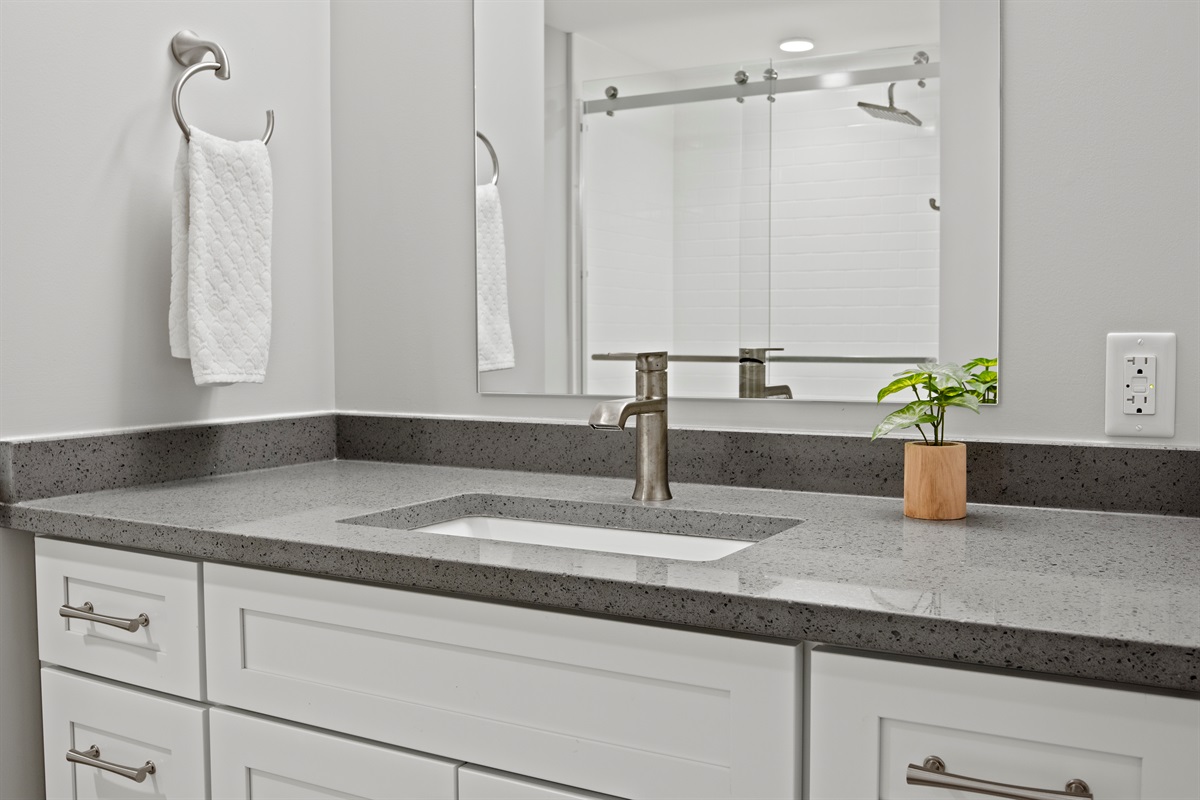 Elegant vanity with quartz countertop, brushed nickel fixtures, and a touch of greenery for a spa-like vibe.