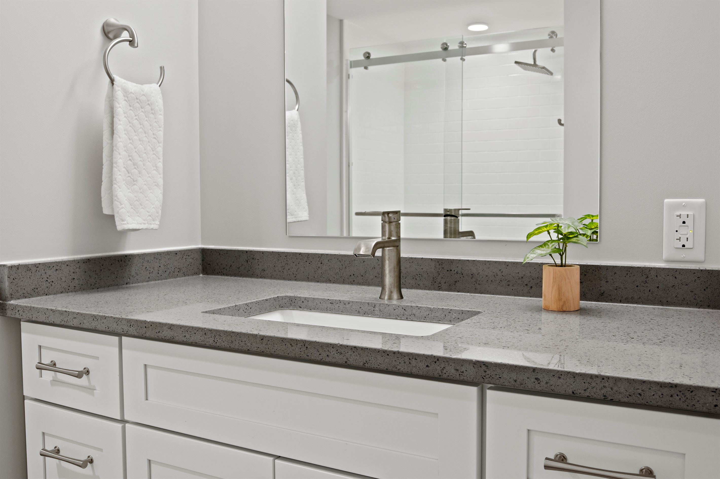 Elegant vanity with quartz countertop, brushed nickel fixtures, and a touch of greenery for a spa-like vibe.