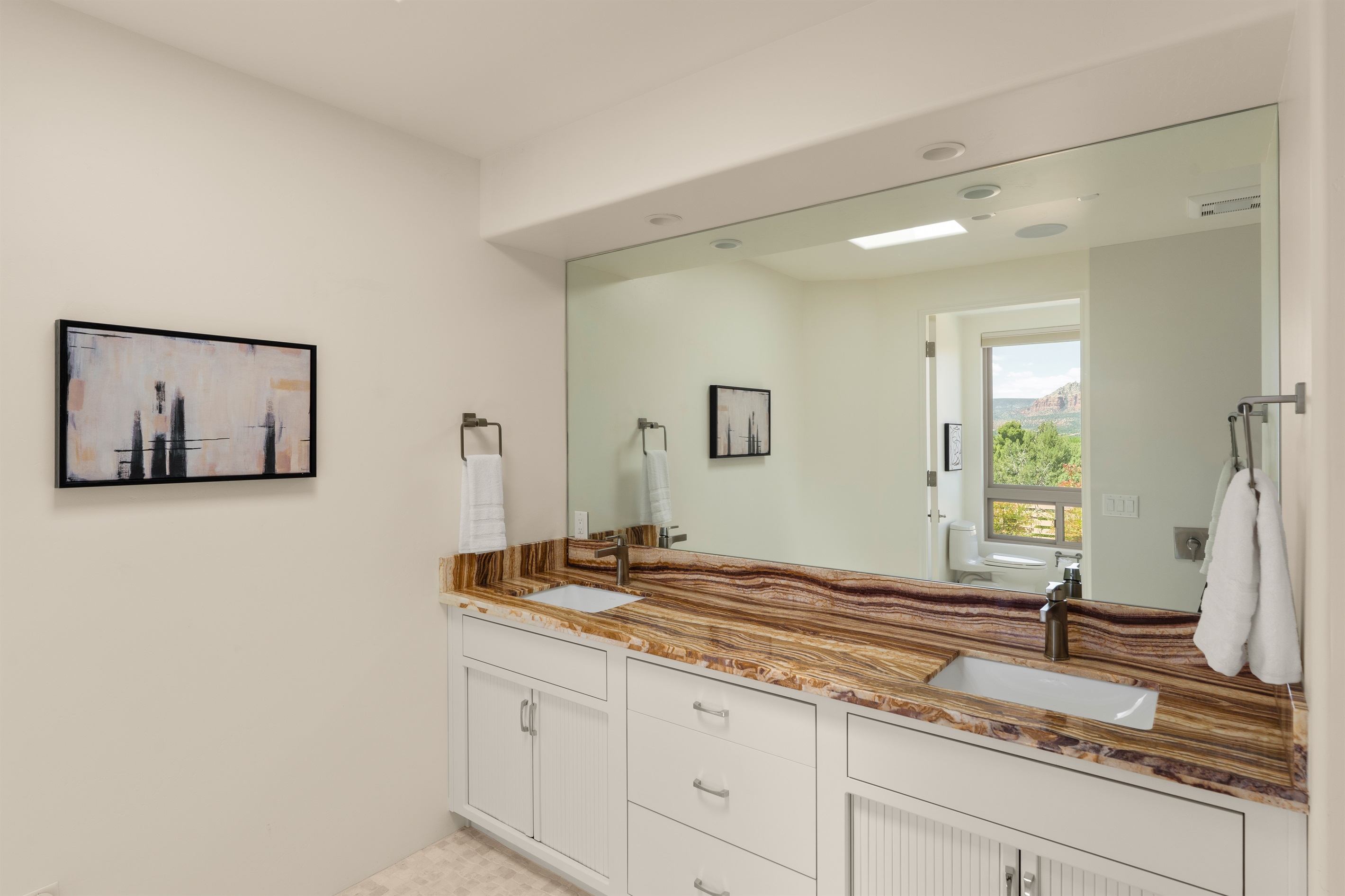Even the vanity comes with a view! Freshen up in this bright, luxurious bathroom featuring striking stone details and a massive mirror that perfectly catches the reflection of the Sedona red rocks.