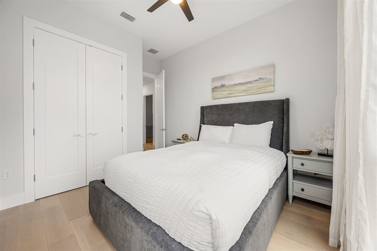 This queen bedroom features double doors that open to a spacious closet, offering a charming and functional space for guests to relax and store their belongings.