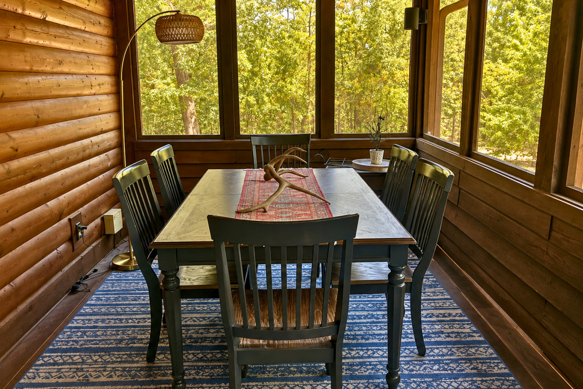 Another dining area in the screened-in porch gives the group even more room to gather, with plenty of seating and wooded views just beyond the screened surroundings.