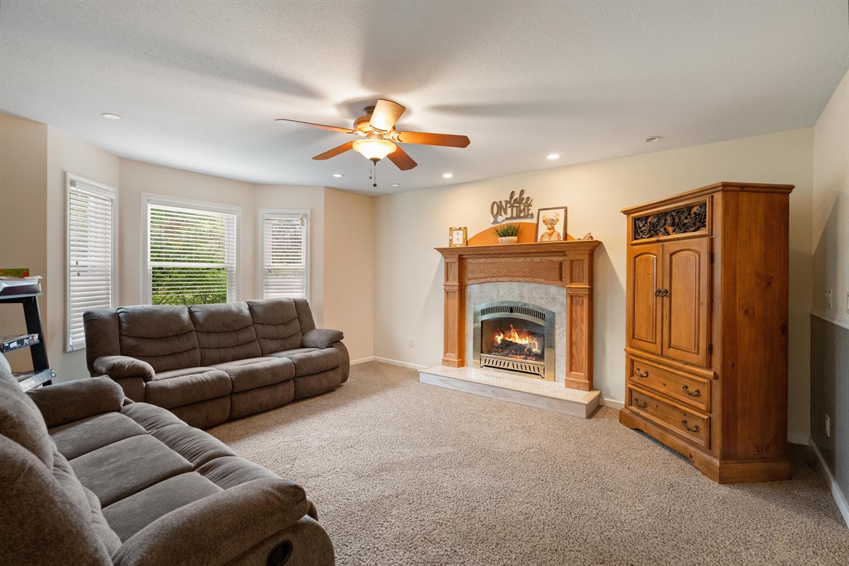 A Cozy 1st floor family room with reclining couches, smart TV, gas fireplace, and family board games