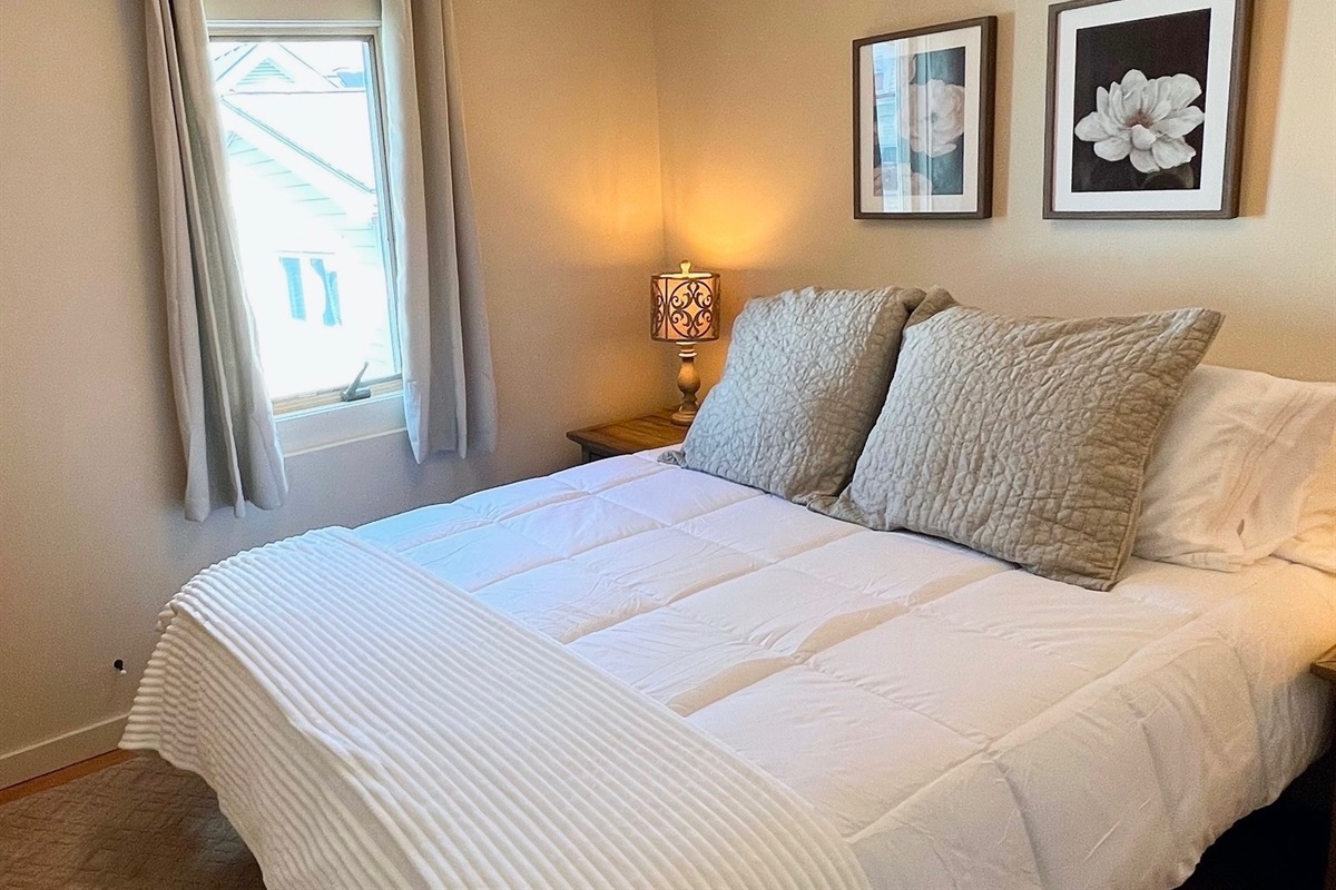 The second guest bedroom also features a queen bed with high quality linens and coastal decor.