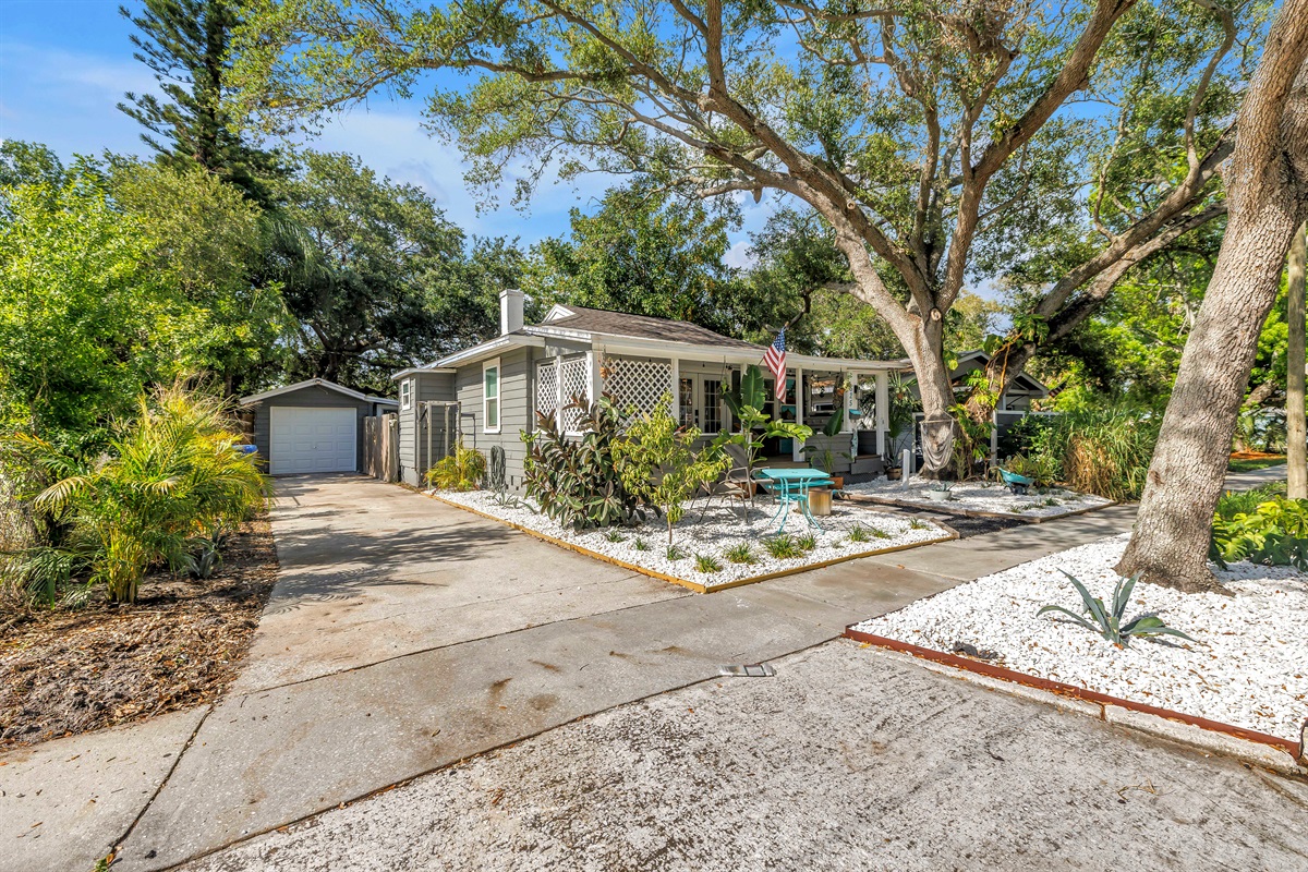 Charming exterior with a welcoming front porch, landscaped yard, outdoor seating, and a peaceful garden-style setting.