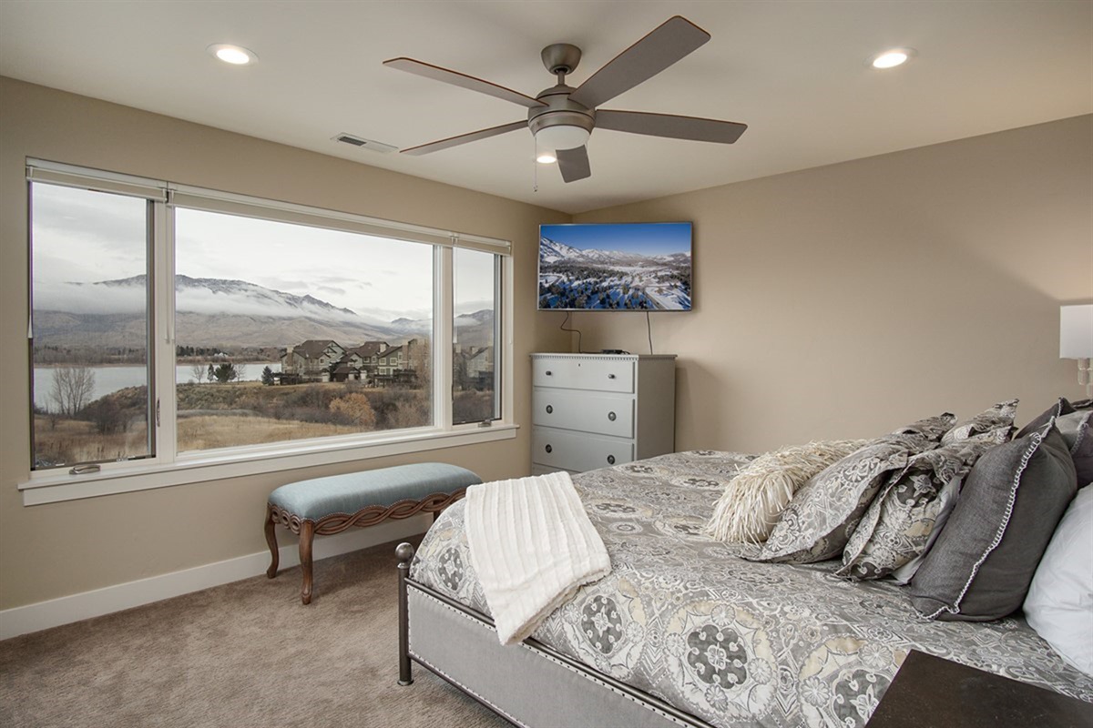 Spacious bedroom with oversized windows showcasing beautiful lake and valley views.