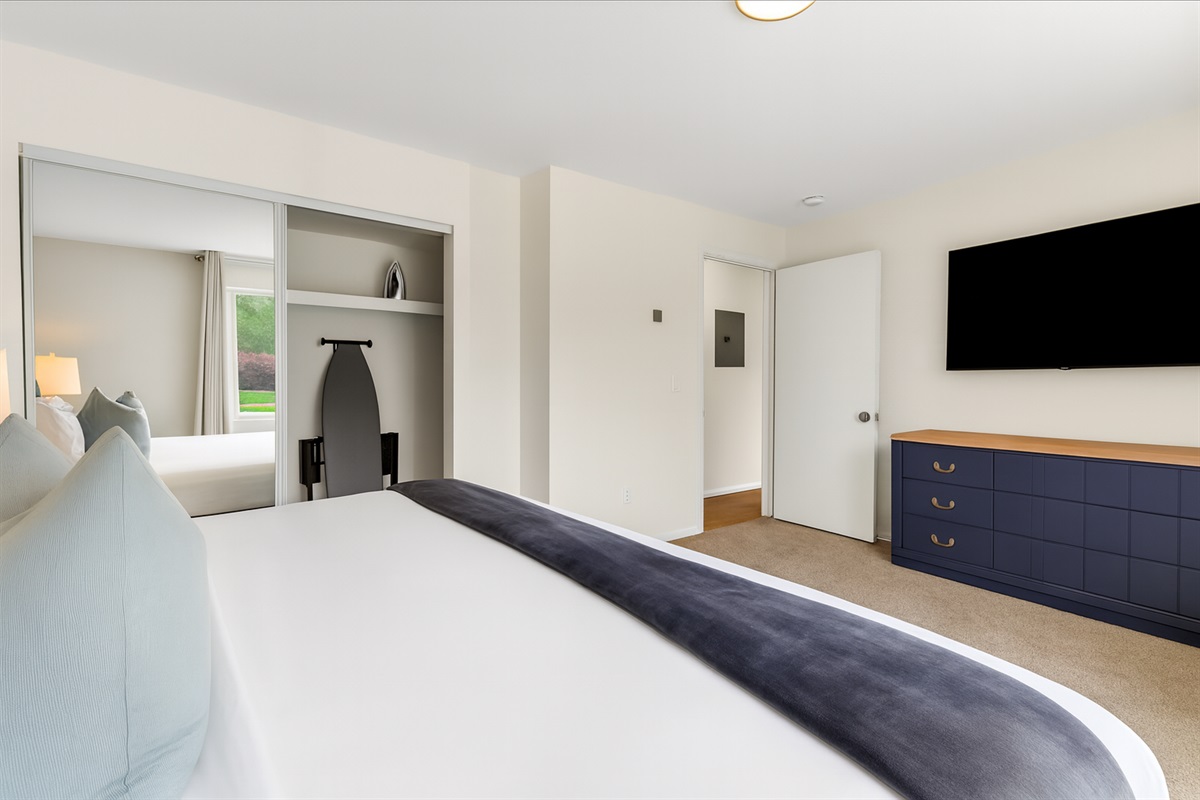 Spacious bedroom with Smart TV, dresser, and plenty of natural light for your comfort.