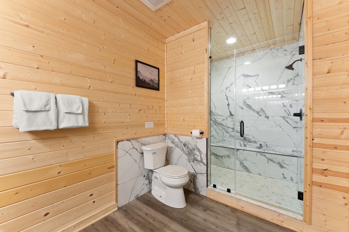 Lower-level full bathroom featuring dual vanity sinks, elegant mirrors, and a spa-like shower area for added comfort and convenience.