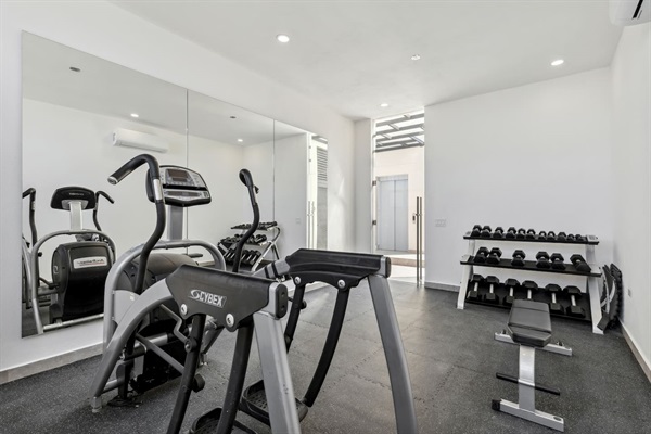 Stay fit in this modern Cabo gym, equipped with a treadmill, weight bench, and dumbbells, plus a mirrored wall for form checks. Perfect for maintaining your workout routine during your Mexico getaway.