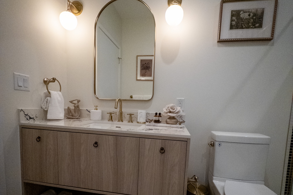 A hotel-style vanity with a wide mirror, brushed-gold faucet and rolled towels stocked and ready for you.