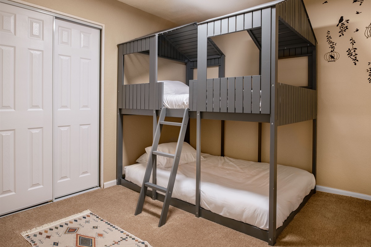Designed with little adventurers in mind, this fun bunk room features a custom cabin-style frame and cozy bedding for the perfect sleepover vibe.