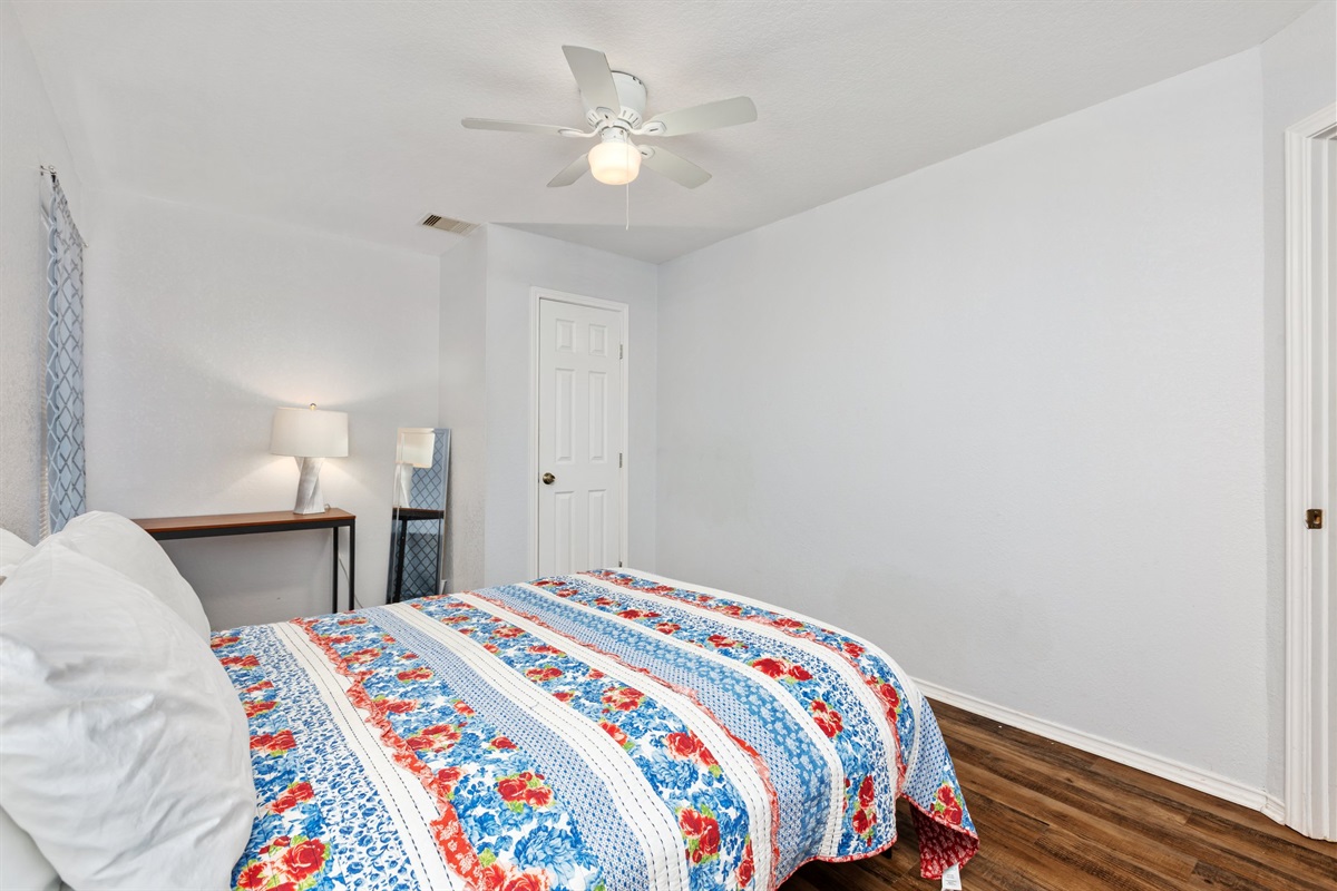 Queen bedroom with hotel-quality linens, ceiling fan, hardwood floors, and clothing storage. Extra pillows and blankets provided. Current decorative blankets, bedding, and wall art are not shown in these photos.