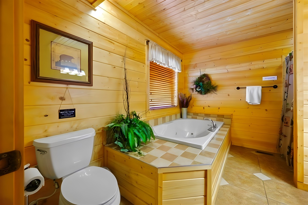 Bathroom #1 – Slip into a soothing soak features a spacious jetted tub surrounded by rustic charm. This cozy bathroom invites you to unwind and let the mountain calm take over.