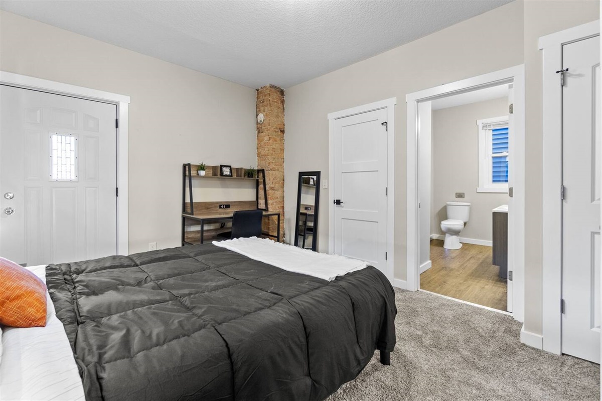 Inviting bedroom with a plush bed and a functional desk, perfect for work or relaxation.