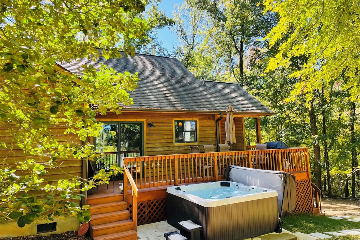 Back deck with dining table, grill, and hot tub