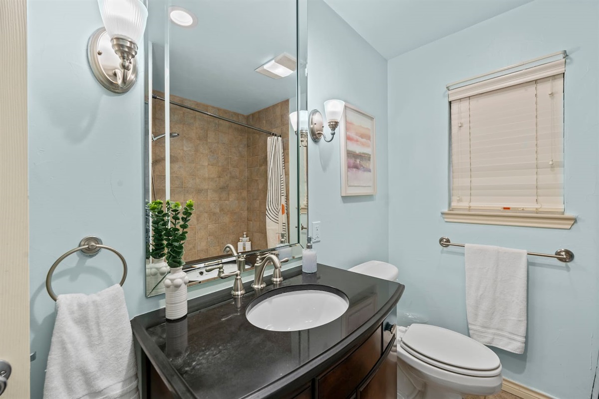 Start your day in this sleek bathroom featuring a spacious granite vanity, modern lighting, and spa-inspired vibes.