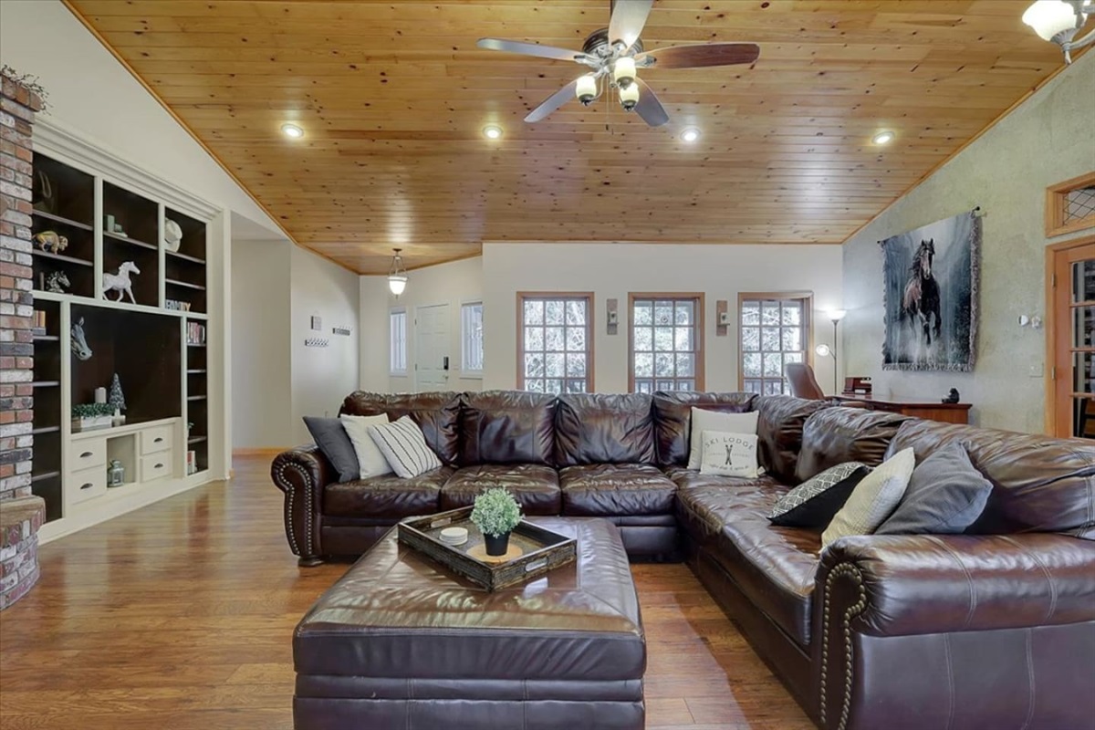 Living room with leather sectional seating, wood ceilings, and room for everyone to gather.
