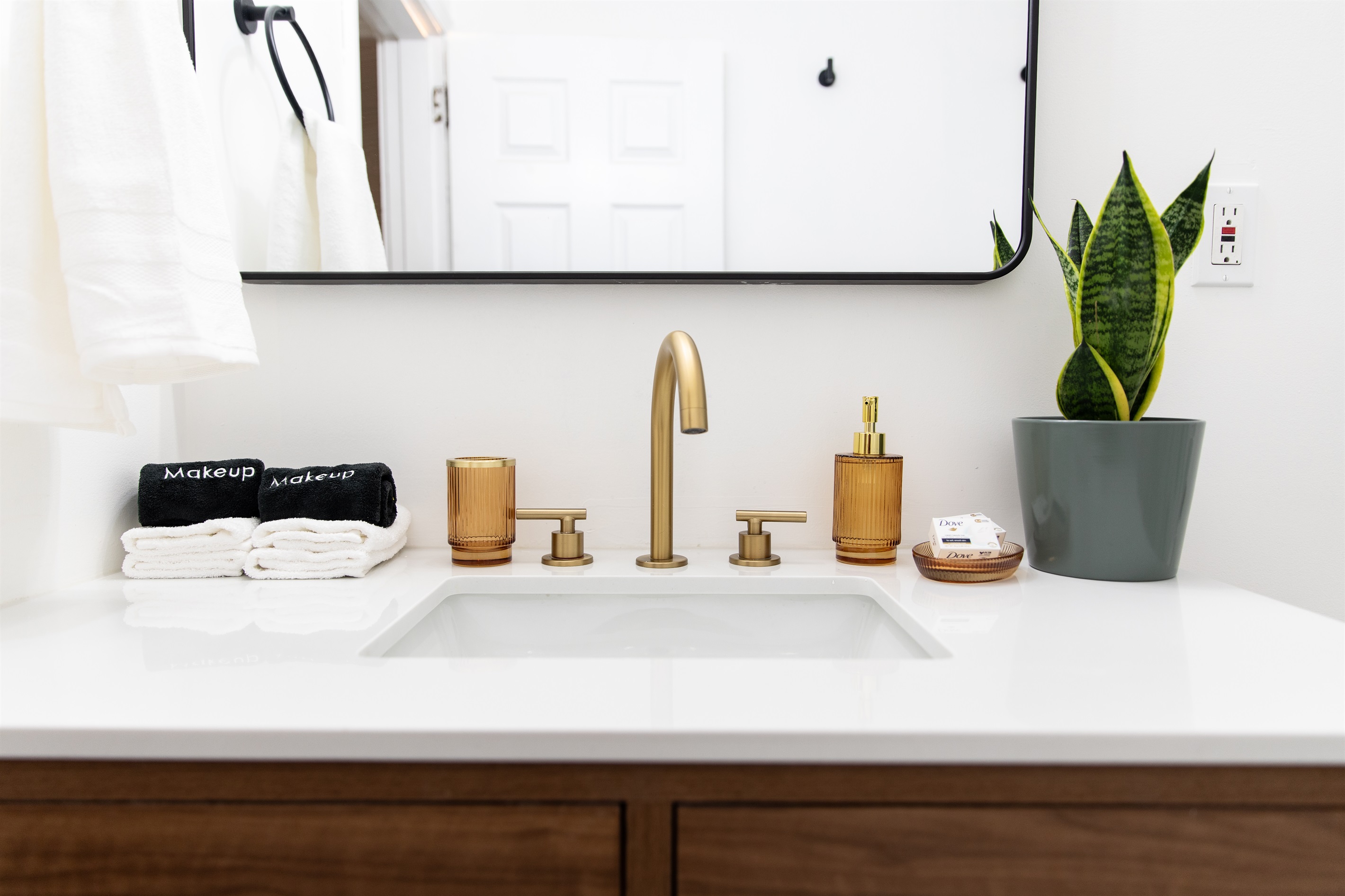 Vanity with gold fixtures, fresh towels, and thoughtful touches including designated makeup cloths for guest convenience.