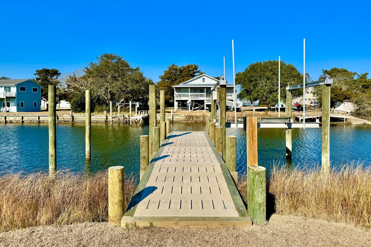 Private backyard dock with boat lift and fillet table, fenced-in backyard, fire pit with Adirondack chairs, hammocks, propane grill, picnic table, outdoor shower, expansive waterfront back deck with table and seating, neighborhood boat ramp and dock