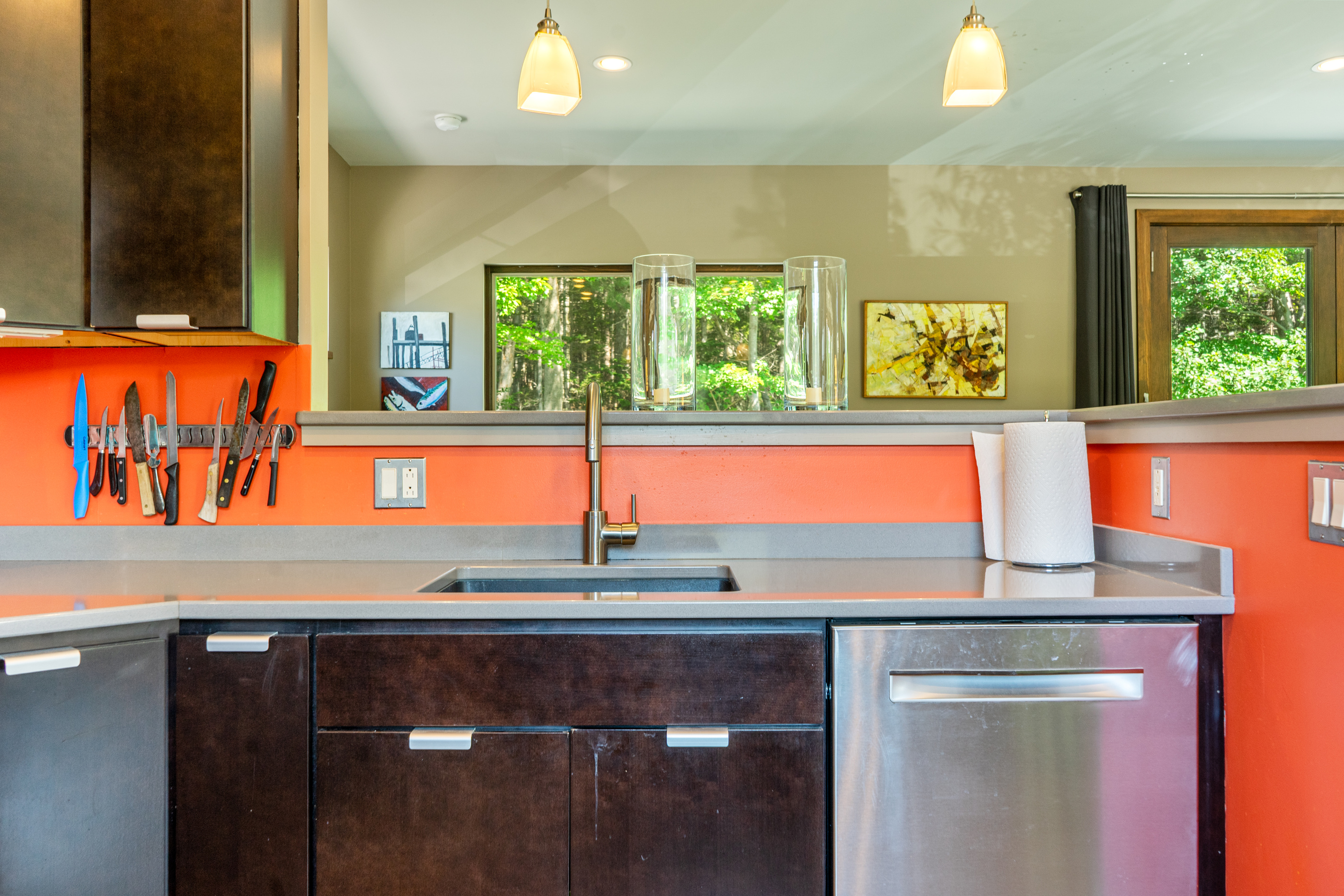 Open-concept prep space in the Social Heart. Featuring an undermount sink, magnetic knife bar, stainless dishwasher, and a wide pass-through counter that keeps the cook connected to group living and dining at "The Crag."