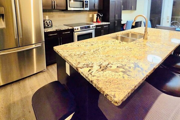 Stylish kitchen with granite island, SS appliances, and bar seating.