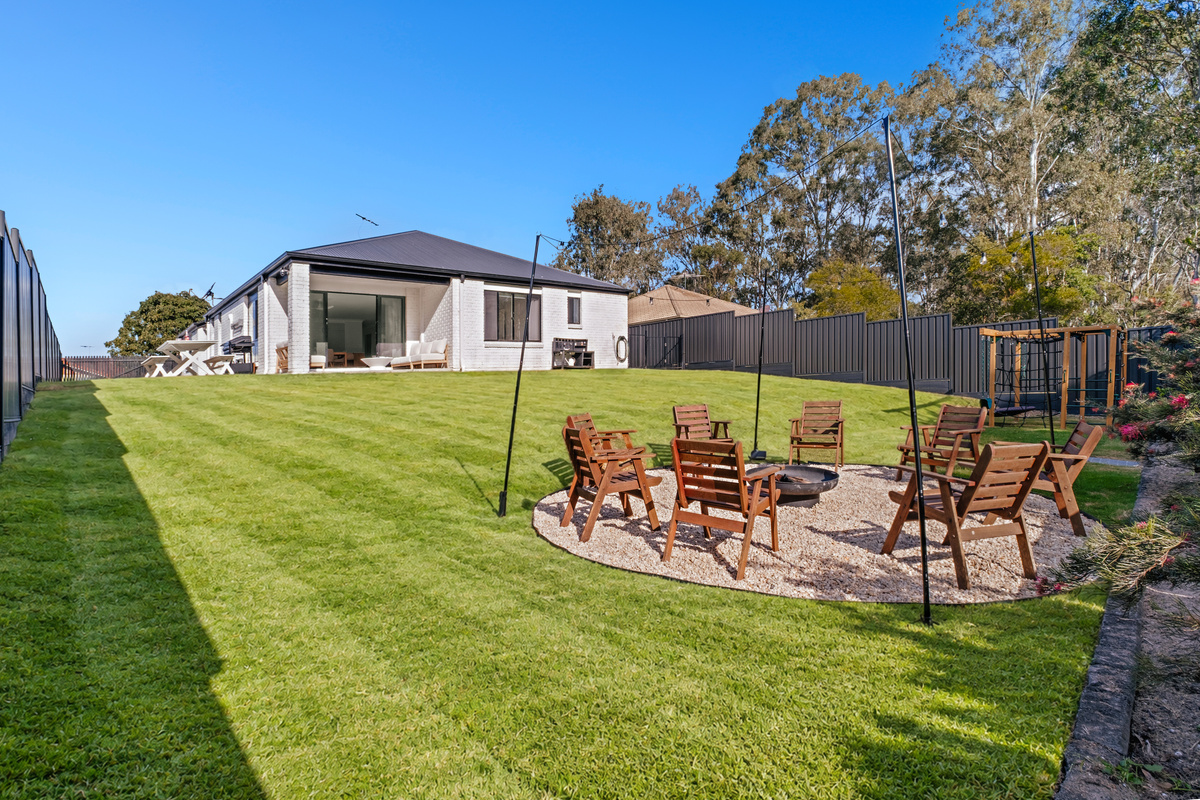 An inviting outdoor space with a fire pit, generous lawn and jungle gym for the kids.