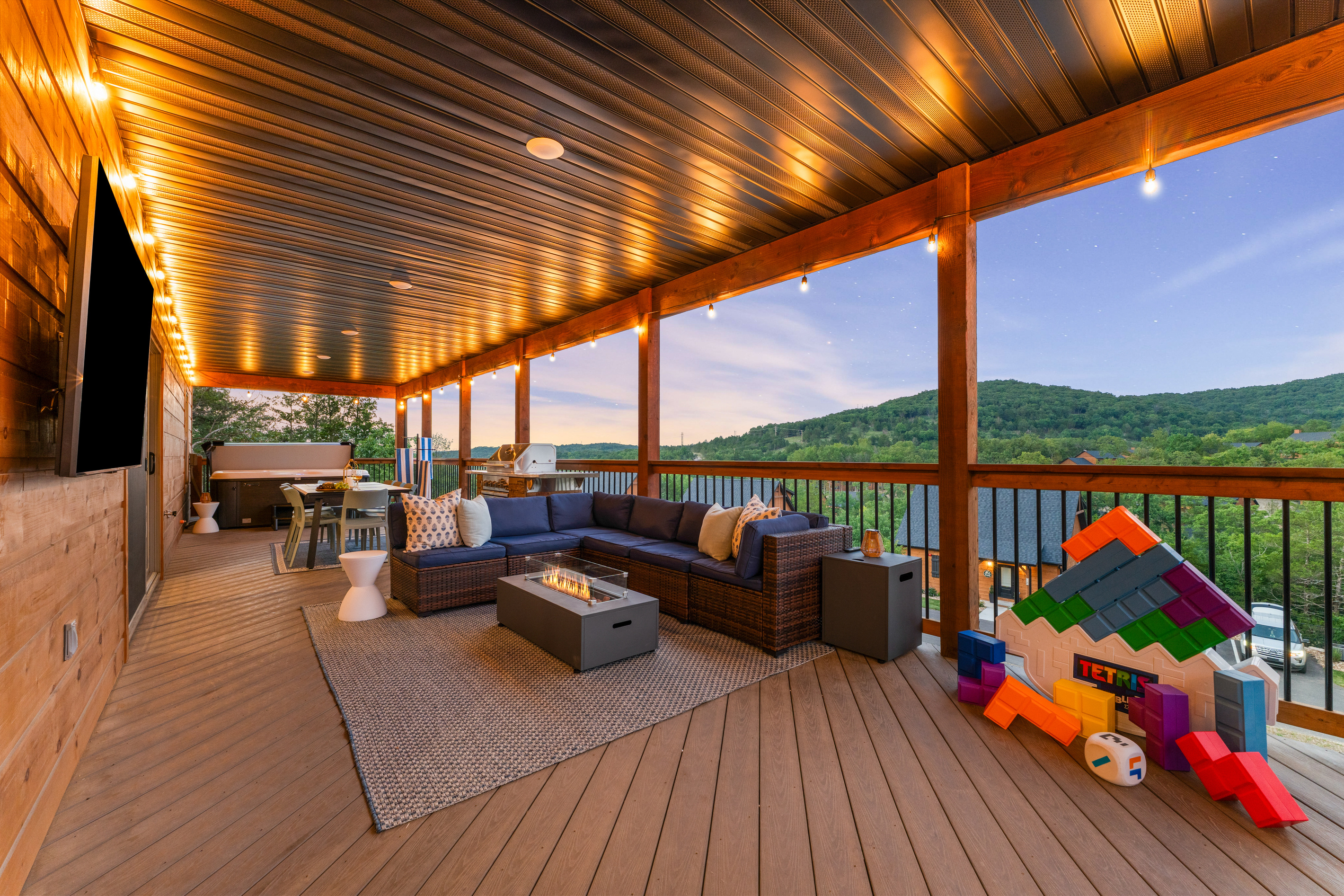 String lights, a starry sky, hot tub, fire table and an outdoor Smart TV keep the covered deck going after dark.