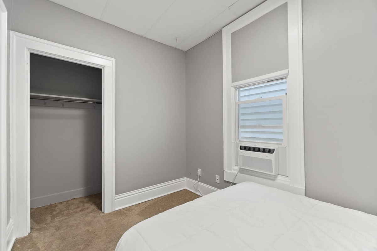 Bedroom with an open closet and window AC unit.